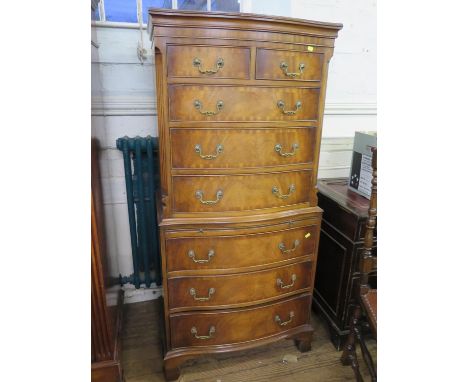 A reproduction crossbanded mahogany serpentine tallboy, with two short and three long graduated drawers over a brush slide an