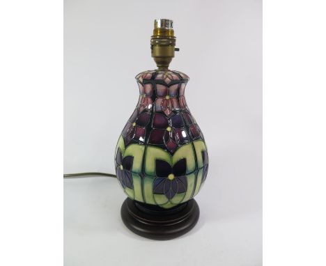 A Moorcroft violets pattern table lamp, with purple flowers on a green ground, 22 cm high 