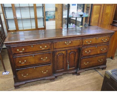 A George III oak and mahogany crossbanded dresser, the moulded top over three frieze drawers above a pair of panelled doors f