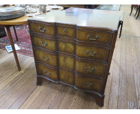 A reproduction mahogany chest of drawers, with ebony stringing, the shaped front with four graduated drawers on outsplayed br