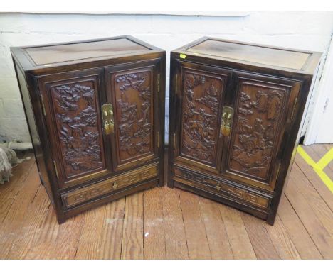 A pair of Chinese hardwood side cabinets, possibly Huanghuali, the panelled tops over a pair of carved panelled doors depicti