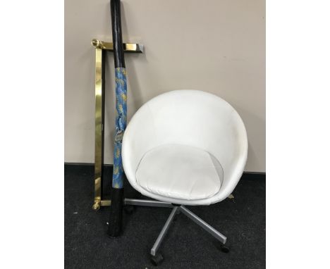 A brass fire curb together with a white vinyl chair and a didgeridoo