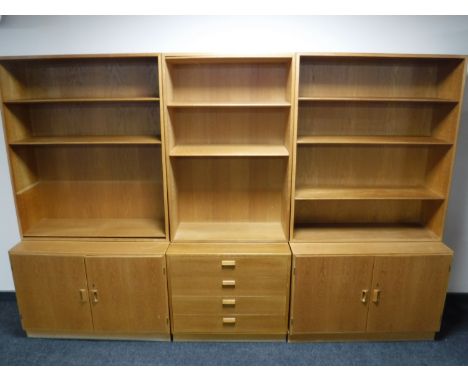 A mid twentieth century light oak three part bookcase, fitted with drawers and cupboards beneath 