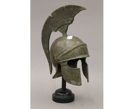 A heavy cast bronze sculpture of a Greek or Spartan helmet with traditional Greek motifs on an ebonised stand. 35 cm high ove