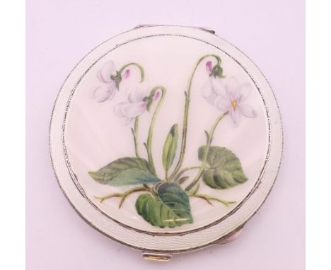 A silver and enamel compact of circular form, painted with a flowering plant, Birmingham 1955. 7.5 cm diameter. 78.7 grammes 