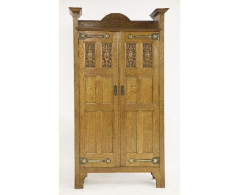 An Arts and Crafts oak hall cupboard, designed by Shapland & Petter, the raised top over panelled doors, with patinated coppe