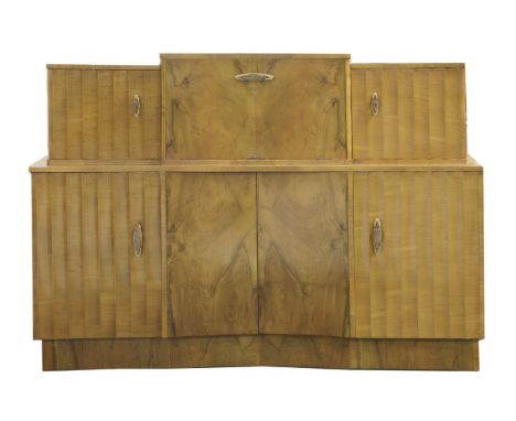 An Art Deco walnut sideboard,the central raised section opening to reveal a tinted glass-panelled cocktail serving shelf, fla