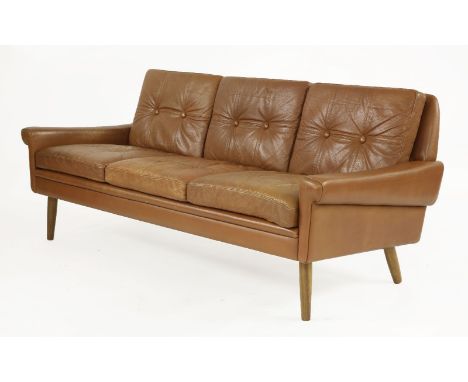 A tan leather three-seater settee,with button back and seat, raised on turned supports,184cm wide