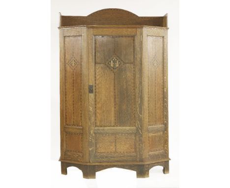 An Arts and Crafts oak wardrobe, designed by Shapland & Petter, the raised top with chequer banding to the panelled door and 