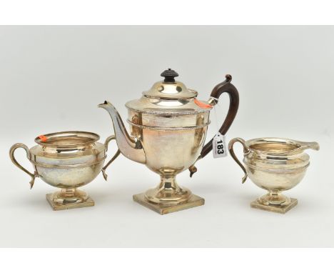 AN EARLY 20TH CENTURY SILVER THREE PIECE TEA SET, comprising of a teapot, sugar bowl and milk jug, each piece raised on a squ