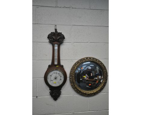A CIRCULAR GILT FRAMED CONVEX WALL MIRROR, diameter 52cm, along with a carved oak barometer (condition report: some minor los