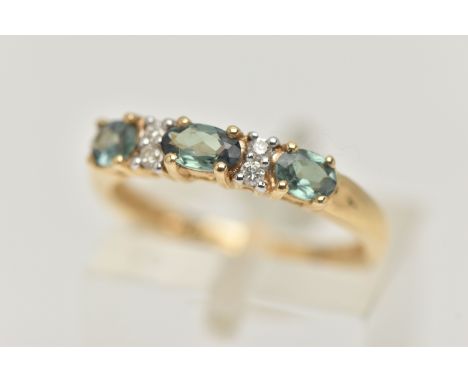 A 14CT GEMSTONE RING, designed as three oval cut green gems, assessed as topaz, interspaced by a total of four brilliant cut 