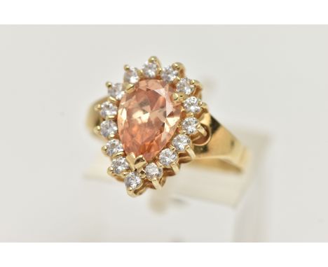 A DRESS RING, designed as a central pear shape peach cubic zirconia within a colourless circular cubic zirconia surround, Hun