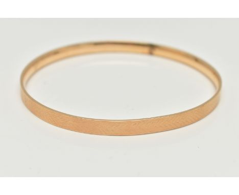 A 9CT GOLD METAL CORE BANGLE, engine turned pattern, stamped '9ct gold solid metal core', approximate internal diameter 76.6m