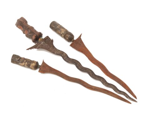 THREE KRIS DAGGERS
One example with carved wood scabbard and hilt, and jewelled hilt clip; the other two examples, a near pai