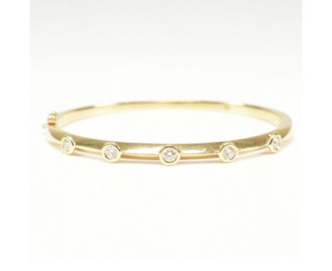 An 18ct yellow gold &amp; diamond bangle bracelet. The hinged bangle having five round cut bezel set diamonds to a knife edge