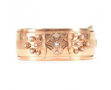 An early 20th Century 18ct gold and diamond bangle. The hinged bangle set with rose cut diamonds in a spray design to a wide 