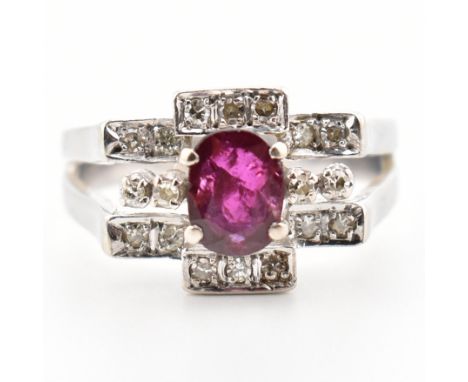 An Art Deco style white gold ruby and diamond cluster ring. The ring set with a central oval cut ruby, framed by terraced set