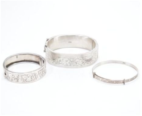 A group of three 925 silver bangles. The lot to include an expandable / christening bracelet with heart &amp; flower design &