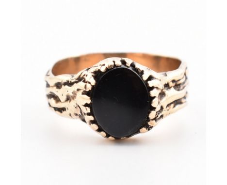 A rose metal and onyx signet ring. The ring having an oval onyx plaque set within a naturalistic setting to textured shank. S