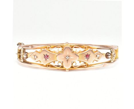 An antique 9ct rose &amp; yellow gold, diamond &amp; red stone bangle bracelet. The hinged bangle formed of two bands spaced 