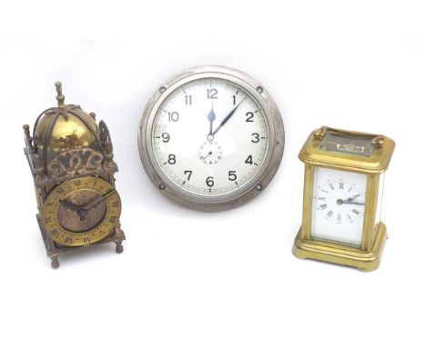 A group of three clocks, including a small brass carriage clock with key, a brass cased lantern clock, and a white metal Ital