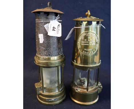 Two brass miner's safety lamps, one unnamed and appearing well used, the other by Protector Lamp and Lighting Company Ltd and