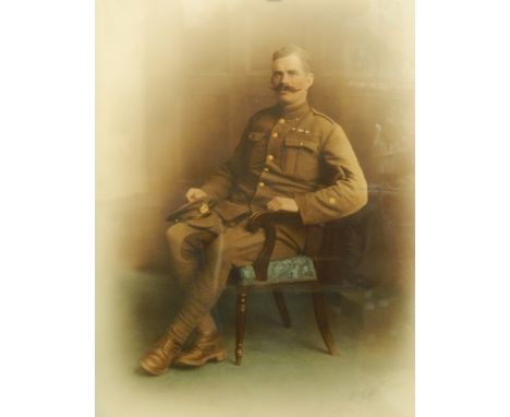 Early 20th century coloured portrait photograph of a seated soldier in army uniform, with indistinct studio signature, 58cm x