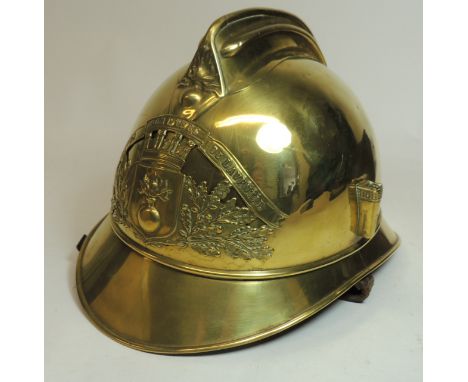 A French fire helmet, the brass helmet with applied badge, plume holder to one side with original leather lining and chin str