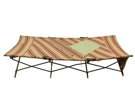 A First World War British Army officer's folding campaign bed, with original red and white striped fabric and a green field-p
