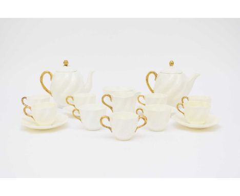 A Coalport tea service, early 20th century, plain white with gilt handles, of fluted form, comprising two teapots and covers,