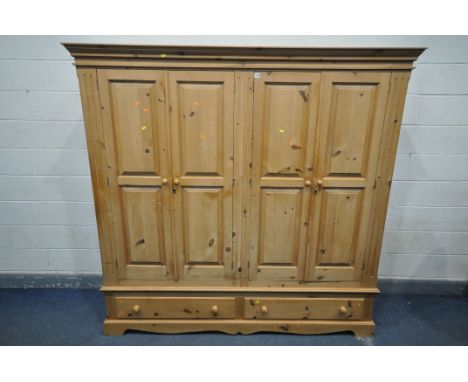 A LARGE PINE FOUR DOOR WARDROBE, with overhanging cornice, and two long drawers, width 204cm x depth 59cm x height 196cm