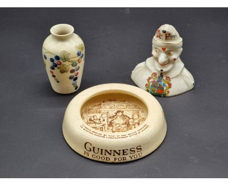 A small early William Moorcroft vase, 8cm&nbsp;high; together with an Arcadian China Mr Punch; and a Guinness ashtray. (3)