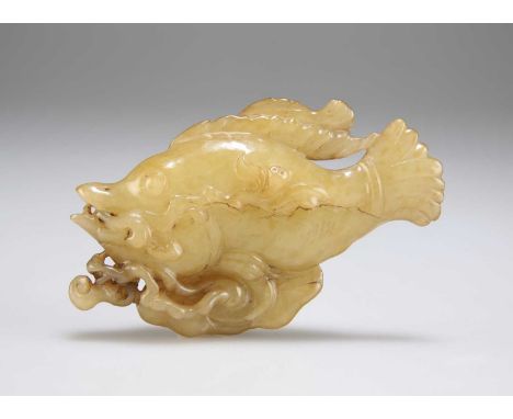 A CARVED JADE FISH GROUP depicting a large and a small fish to a foliate ground. 9.2cm wideNatural crack in the surface but o