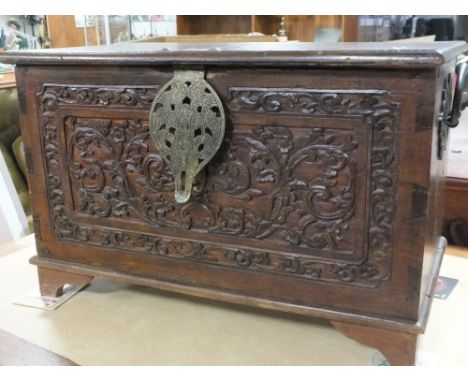 A HARDWOOD HEAVILY CARVED TRUNK WITH FLORAL DETAIL, WROUGHT IRON HANDLES IN  ORIENTAL DESIGN