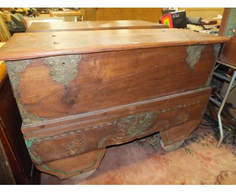 AN UNUSUAL HARDWOOD HEAVILY CARVED TRUNK WITH FLORAL DETAIL, ON WHEELS W- 133 CM X D- 55 CM
