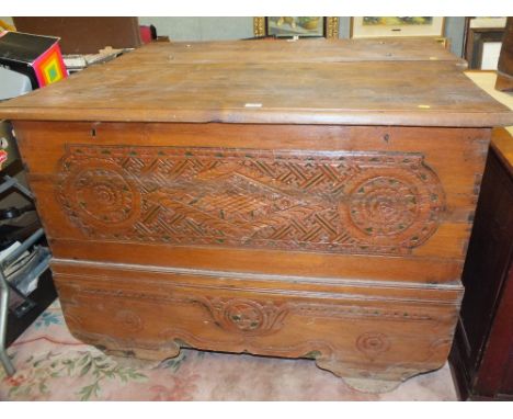 AN UNUSUAL HARDWOOD HEAVILY CARVED TRUNK WITH FLORAL DETAIL, ON WHEELS W- 126 CM X D-56 CM