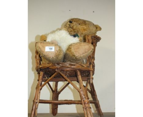 A VINTAGE STRAW FILLED TEDDY BEAR ON WICKER CHAIR 