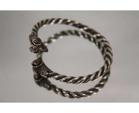 A VINTAGE WHITE METAL TORQ BANGLE WITH RAMS HEAD DETAIL