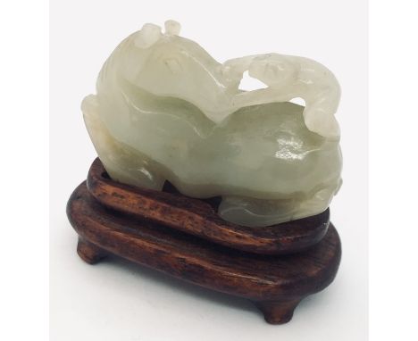 A pale green jade horse and monkey, carved with the monkey holding onto the horses turned head. With a small hardwood stand. 
