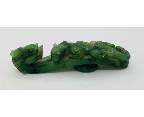 A green jade Chinese belt hook decorated with a dragon head and winged dragon. 8.2cm.