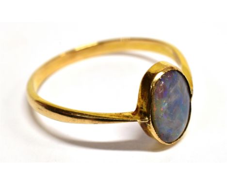 A BLACK OPAL SINGLE STONE YELLOW GOLD RING The old cabochon cut opal 10mm x 7mm, blue green play of colour with orange red fl