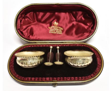A CASED PAIR OF VICTORIAN SILVER SALTS AND SPOONS of shallow cauldron form with spiral lobes and scroll decoration with white