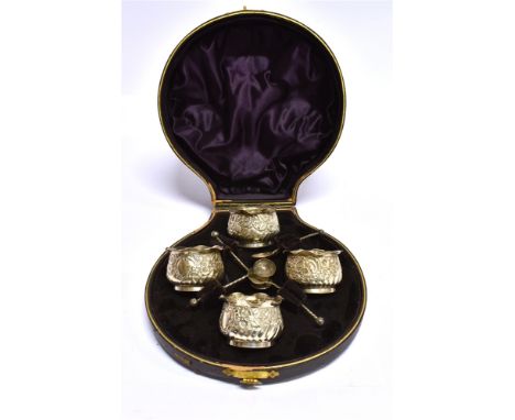 A CASED SET OF FOUR VICTORIAN SILVER SALTS AND SPOONS the cauldron form salts spiral fluted with embossed floral decoration a