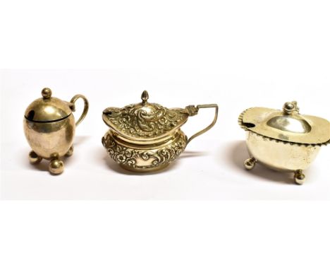 THREE ASSORTED SILVER MUSTARD POTS comprising an egg shape plain form on three ball feet, hallmarked Chester 1911, a cushion 