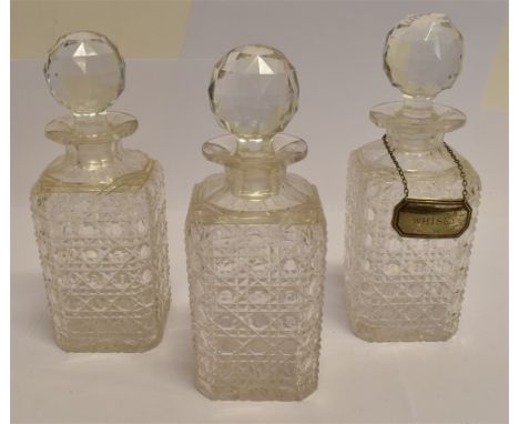 THREE MATCHING HOBNAIL CUT DECANTERS AND STOPPERS  22cm high, together with a silver 'Whisky' label