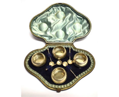 A VICTORIAN CASED SET OF FOUR SILVER SALTS AND SPOONS  of circular cauldron form, on three ball feet, stipple engraved border