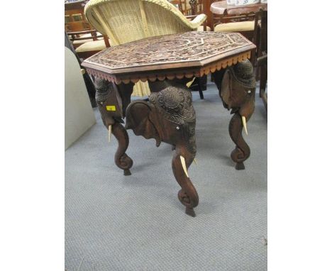 A mid 20th century carved hardwood octagonal occasional table, raised on elephant head and trunk legs with bone tusks, 