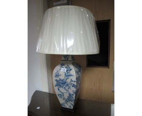 A PORCELAIN TABLE LAMP the white and blue ground decorated with flowerheads and foliage raised on a hardwood base with pleate