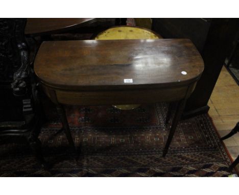 A GEORGIAN MAHOGANY FOLD OVER CARD TABLE the rectangular bowed top containing a baize lined interior above a plain frieze on 